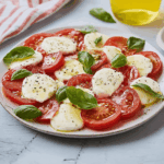 Mozzarella mit Tomaten Rezepte – Frisch, einfach & unwiderstehlich gut 4 Mozzarella mit Tomaten Rezepte: Detail mit Pfeffer, Basilikum und grünem Tuch im Vordergrund