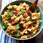 Nudelsalat mit Rucola und getrocknete Tomaten: dein ultimatives Sommer-Highlight 4 Servierter Nudelsalat mit Rucola und getrocknete Tomaten in Schüssel