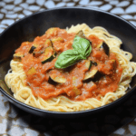 Tomatensauce mit Aubergine und Zucchini einkochen draufsicht in schwarzer Schale mit Spaghetti